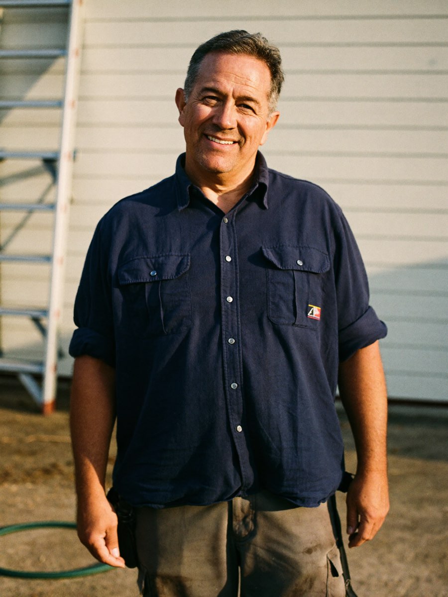 Mark Grumich, owner of ProRosa, standing by a house in late afternoon light.